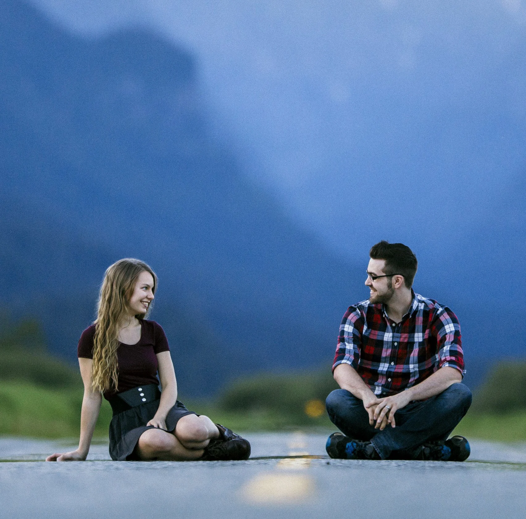 Original portrait of a couple seated beside a mountain road before restoration.
