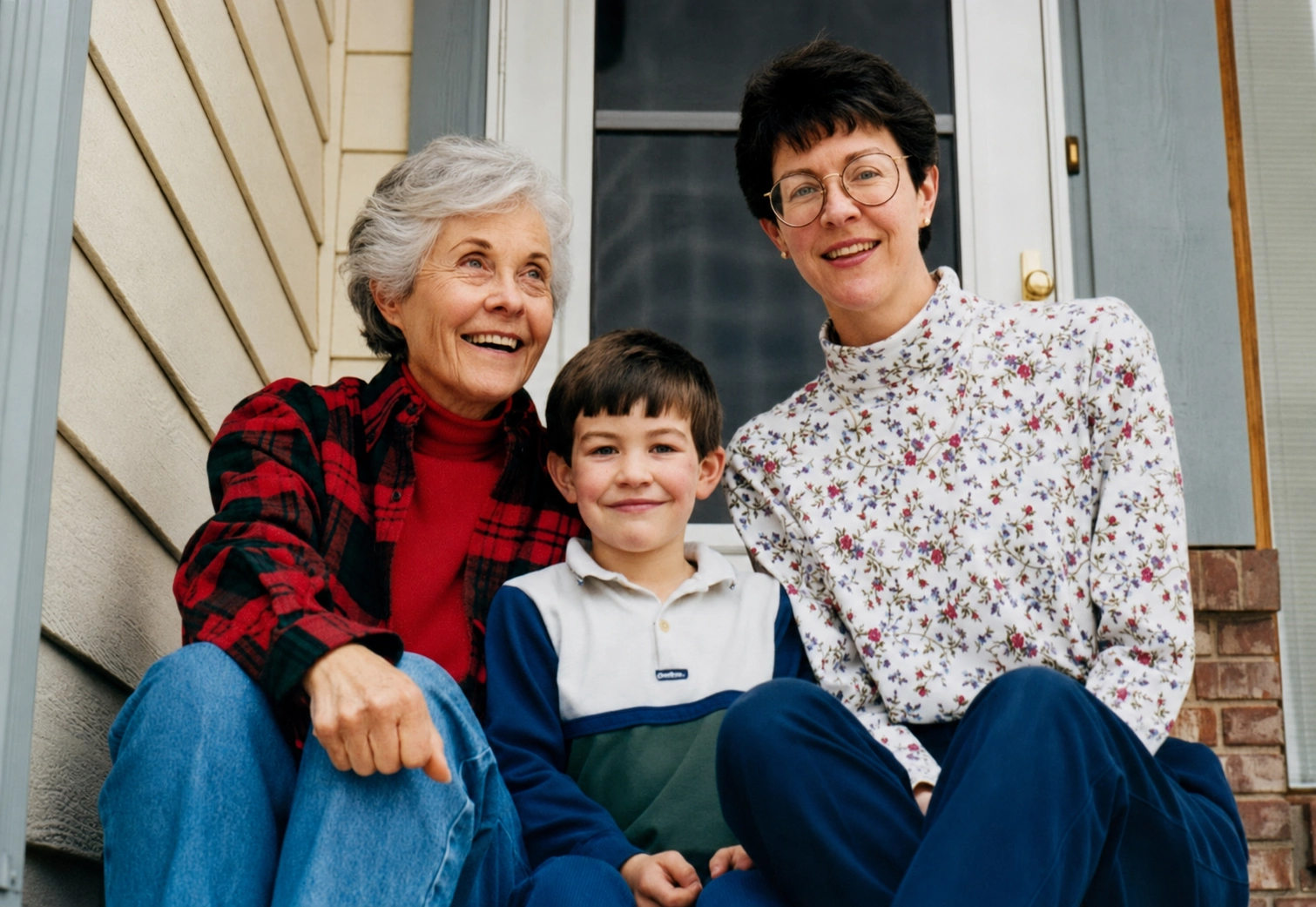 Restored colour portrait of two women and a young boy seated together on a front porch.